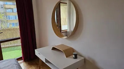 a white dressing table with a mirror and a window at Business Park Retreat: 1BR with Mountain View in Sofia