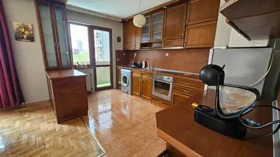 a kitchen with wooden cabinets and a chair on a counter at Business Park Retreat: 1BR with Mountain View in Sofia