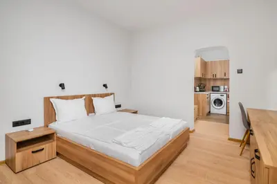 a bedroom with a large bed and a kitchen at Cozy Flats Near Alexander Nevski Cathedral by Flat Mаnager in Sofia