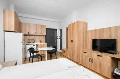 a kitchen with wooden cabinets and a tv and a table at Cozy Flats Near Alexander Nevski Cathedral by Flat Mаnager in Sofia