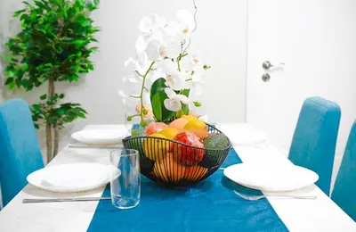 a table with a bowl of fruit on a blue table cloth at 2BR Downtown Suit Next to Nevski Cathedral - AC in Sofia