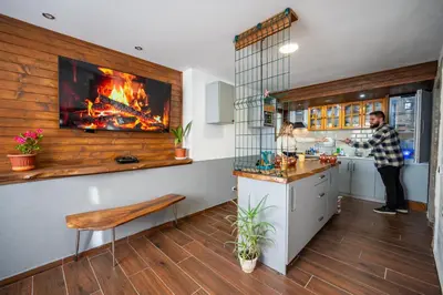 a man standing in a kitchen with a fire in the wall at Къща за гости Приказка in Klisura