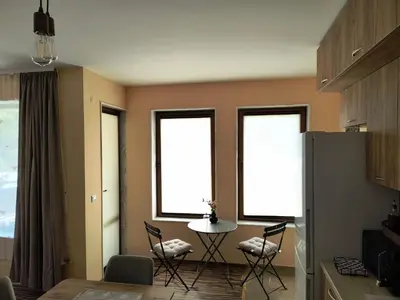 a kitchen with three windows and a table and chairs at Апартамент за гости Александър in Chepelare