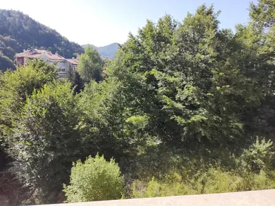 a group of trees with a house in the background at New & Stylish Apartment Axel with Mountain Views in Smolyan