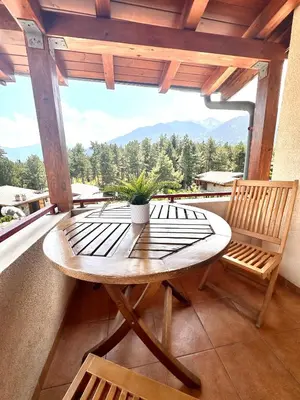 a wooden table and chairs on a balcony with a view at Pirin Golf Mountain View Apartment in Razlog