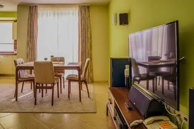 a living room with a dining table and a television at Апартамент Пирин Apartment Pirin in Sandanski
