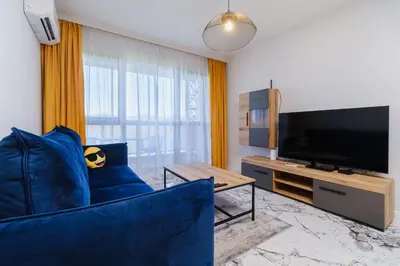 a living room with a blue couch and a flat screen tv at Lauta Forest 1-bedroom apartment in Plovdiv