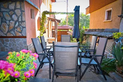 a group of chairs sitting on a patio with flowers at Къща за гости ФЪН ШУЙ 88 in Dobrinishte