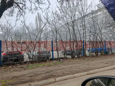 a fence with cars parked in front of a building at Apartment 59 in Sofia