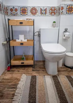 a bathroom with a white toilet and a rug at Boho Apartment Plovdiv with Private Parking Space in Plovdiv