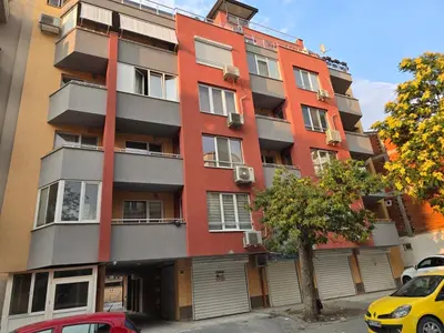 a tall red building with cars parked in front of it at Boho Apartment Plovdiv with Private Parking Space in Plovdiv