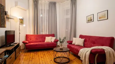 a living room with a red couch and a tv at The Red Sofa City Retreat in Sofia
