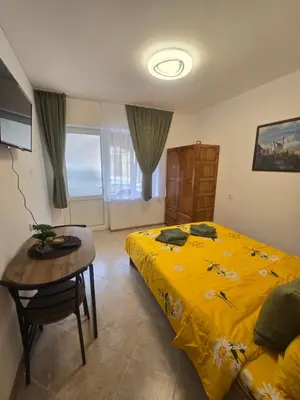 a bedroom with a yellow bed and a table at Къща за гости Кралимаркови Guest house Kralimarkovi in Devin