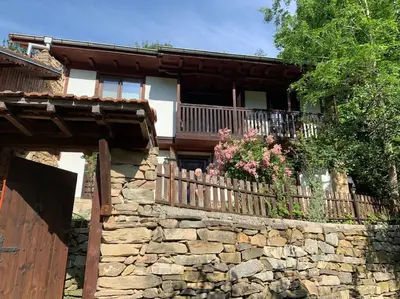 a stone wall in front of a house with a fence at Beautiful Villa in the Rodopi Mountains in Narechen