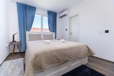 a bedroom with a bed with blue curtains and a window at Serene Luxe Oasis Retreat on the Outskirts by Flat Mаnager in Plovdiv