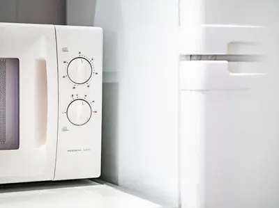 a white microwave oven sitting next to a refrigerator at Cozy 1 bdrm, top center, Solunska near Vitoshka street in Sofia