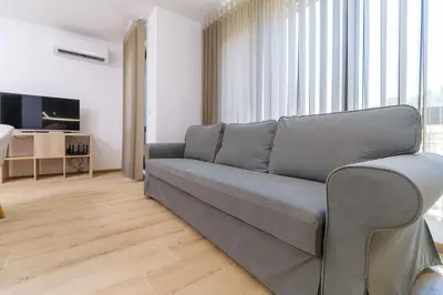 a living room with a couch and a television at Modern 1-Bedroom Apartment with Free Parking in Plovdiv