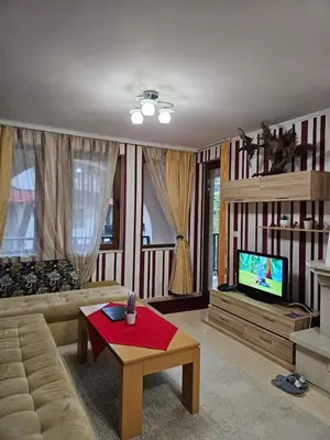 a living room with a couch and a tv at Частен Апартамент Пампорово Гранд Манастира 2Б5 in Pamporovo