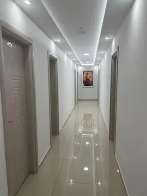 a hallway with white walls and a painting on the wall at Хотел Лилия in Rudozem