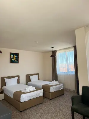 a hotel room with two beds and a chair at City Plaza in Botevgrad