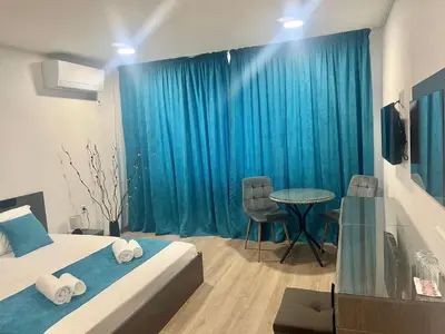 a bedroom with a bed and a table and blue curtains at Къща Росена - стаи за гости in Devin