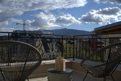 two chairs on a balcony with a view of the mountains at Panorama view free parking in Sofia