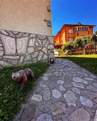 a statue of a bear on the grass next to a stone wall at Къща за гости Димитрови guest house Dimitrovi in Devin