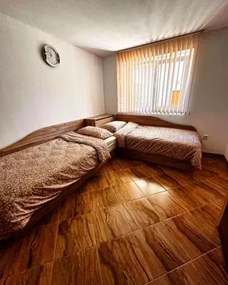 a bedroom with two beds and a window and wooden floors at Къща за гости Димитрови guest house Dimitrovi in Devin