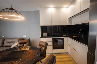 a kitchen with a dining table and a kitchen with white cabinets at Gran Capital - Vodolei Garden, FREE Parking in Sofia