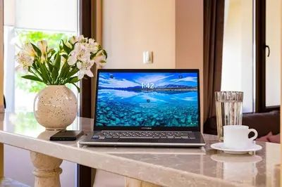 a laptop computer sitting on a table with a vase of flowers at Central Park Apartment Dragan Tsankov in Plovdiv