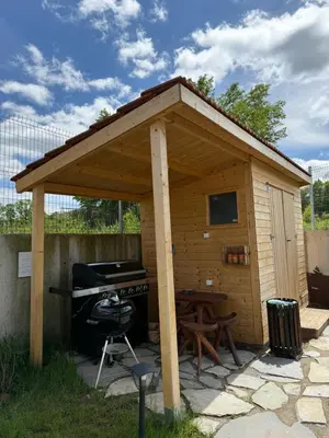 a barbecue shed with a grill and a picnic table at Edelweiss Oreshak in Oreshak