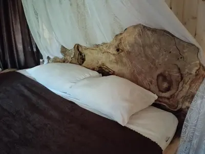 a bed with a tree stump headboard and two pillows at Приказната къщичка на Смърфовете in Krayni Dol