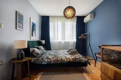 a bedroom with a bed with blue walls and a window at ART-ament, a unique central flat in Sofia