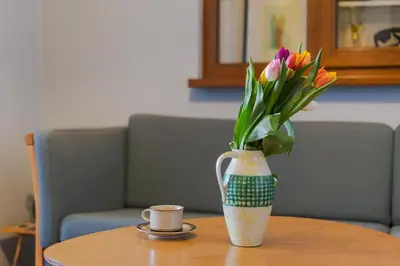 a vase of flowers on a table with a cup at ART-ament, a unique central flat in Sofia