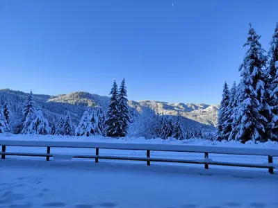 a fence covered in snow with trees and mountains at Panorama Stoykite Belvedere in Stoykite