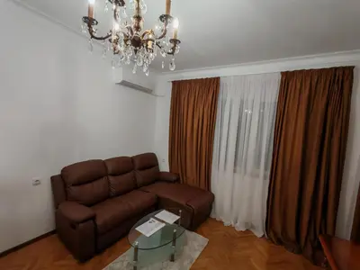 a living room with a brown couch and a chandelier at Apartament 88 in Sofia