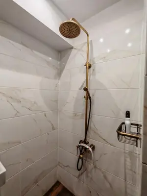 a bathroom with a shower with white marble walls at Apartament 88 in Sofia
