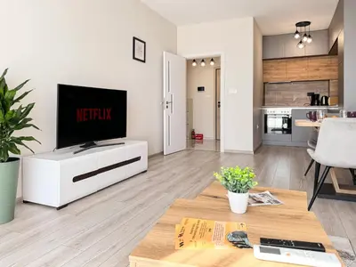 a living room with a flat screen tv on a white cabinet at Modern 1BR Apartment with Free Street Parking and free Gym Pass in Plovdiv