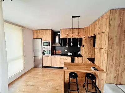 a kitchen with wooden cabinets and a kitchen island with stools at Raya apartment in Plovdiv