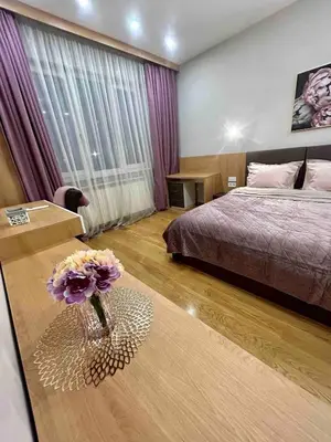 a bedroom with a bed and a vase with flowers on a table at City Center Spacious 2BR near Vitosha Blvd in Sofia
