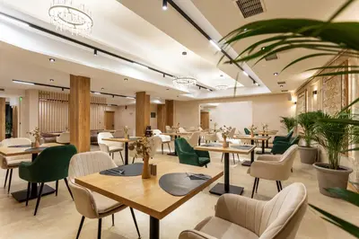 a restaurant with wooden tables and green chairs at AMAR Design Hotel by HMG in Sofia