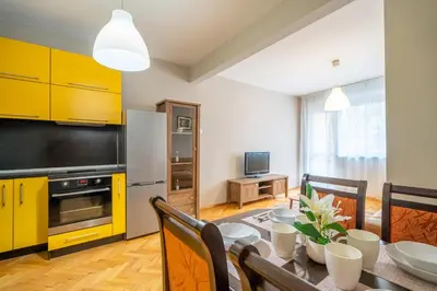 a kitchen with a dining table and yellow cabinets at Pirotska 2-Bedroom 100m2 Apartment in Sofia Center in Sofia