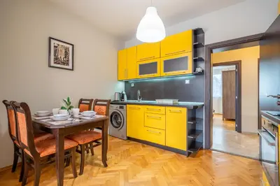 a kitchen with yellow cabinets and a table with chairs at Pirotska 2-Bedroom 100m2 Apartment in Sofia Center in Sofia