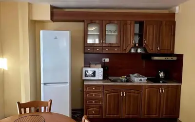a kitchen with wooden cabinets and a white refrigerator at Апартаменти Хармония in Pamporovo