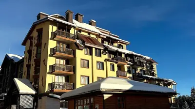 a tall yellow building with balconies on top of a building at Апартаменти Хармония in Pamporovo