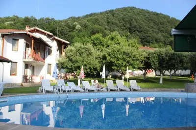 a woman is sitting in chairs next to a swimming pool at By the River Hotel Complex in Balkanets