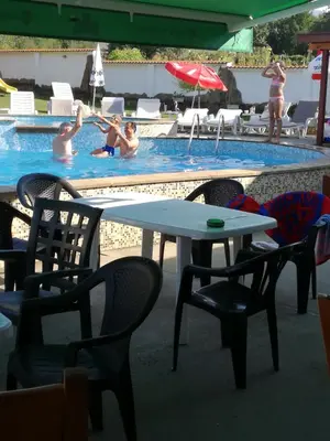 a table and chairs and people in a swimming pool at By the River Hotel Complex in Balkanets