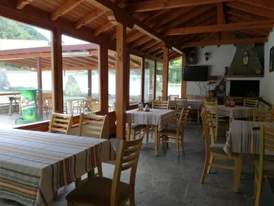 a dining room with tables and chairs and windows at By the River Hotel Complex in Balkanets