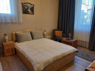 a bedroom with a bed and a chair and windows at Костовският хан in Chepelare
