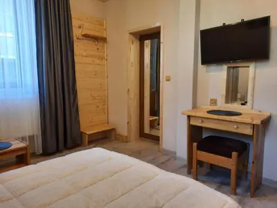 a bedroom with a bed and a desk with a television at Костовският хан in Chepelare